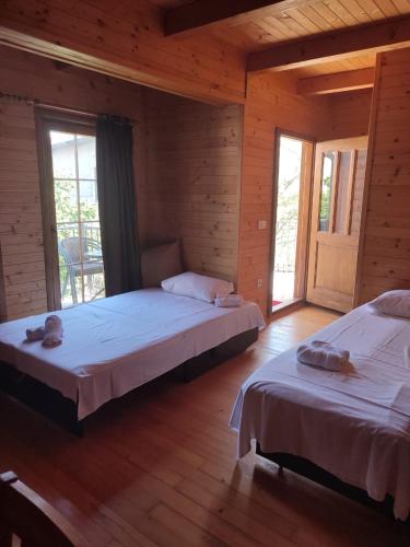 two beds in a room with wooden walls and windows at Lotos - vikendica 1 in Bar