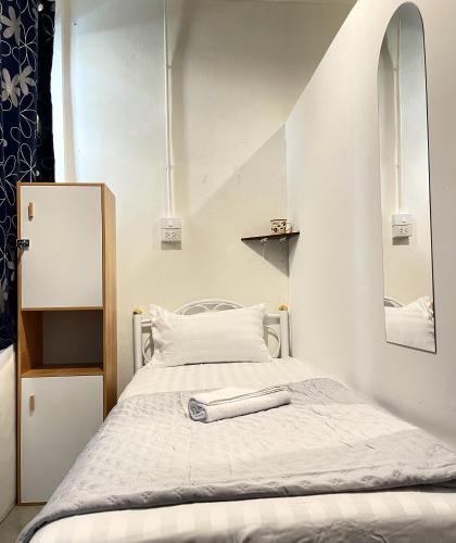 a small bedroom with a bed and a mirror at Moon Pīti in Bangkok