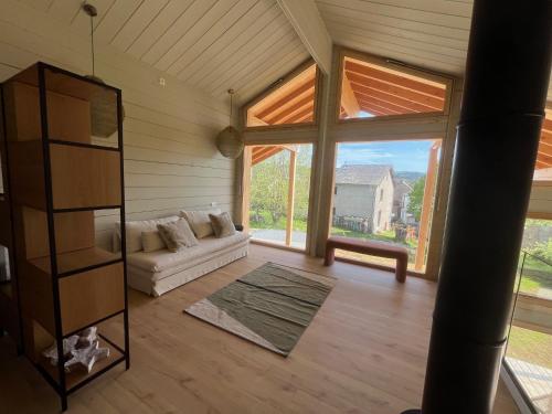a living room with a couch and a large window at Coeur Cévennes Wooden Cottage in Camprieu