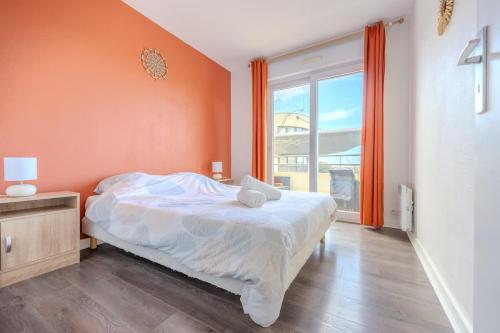une chambre avec un lit avec un mur orange dans l'établissement Le Lagon Bleu - Appartement La Rochelle, à La Rochelle