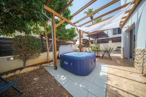 a patio with a large blue tub under a pergola at Seaside Villa Luci with jacuzzi and just minutes away from Ayia Triada beach in Paralimni