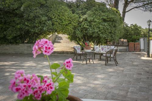 a patio with chairs and a table with pink flowers at Villa Bagolini in Mentana