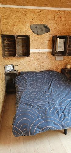 a bed with a blue comforter in a room at Flips et mousse in Gembloux
