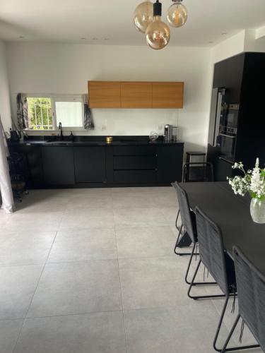 une cuisine avec des armoires noires, une table et des chaises dans l'établissement Apparemment luxueux, à Biot