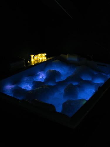 une baignoire remplie d'eau bleue avec des bougies dans l'établissement Parenthèse enchantée sous les toits, à Saint-Étienne