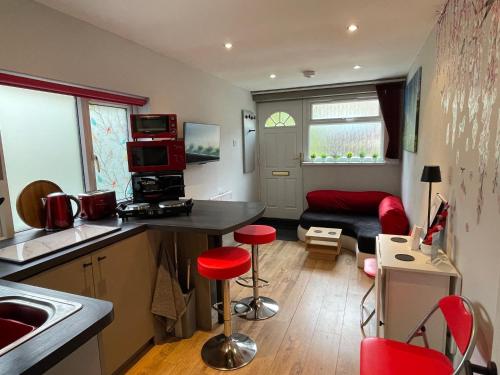 a kitchen and living room with red stools in a room at The Secret Maisonette Rochester in Rochester