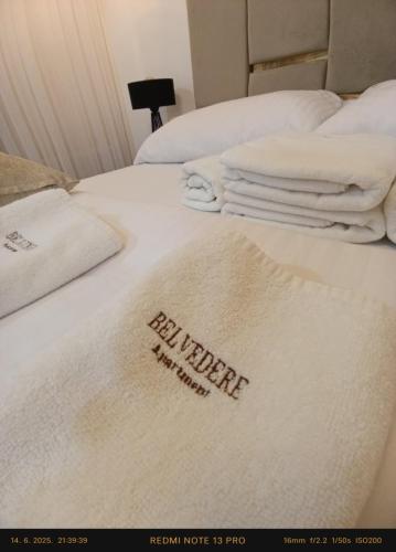 a bed with white blankets and towels on it at Belvedere Apartment in Doboj