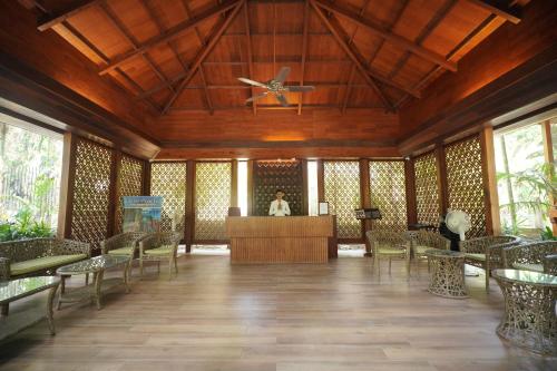 a lobby with a ceiling fan and tables and chairs at Sea Shell Neil in Neil Island