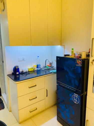 a kitchen with a black refrigerator and a sink at Maati Properties Room 311 in Joār Sāhāra
