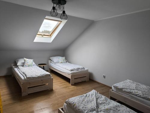 a room with three beds and a window at Apartamenty LilaRóż in Brzozie Polskie