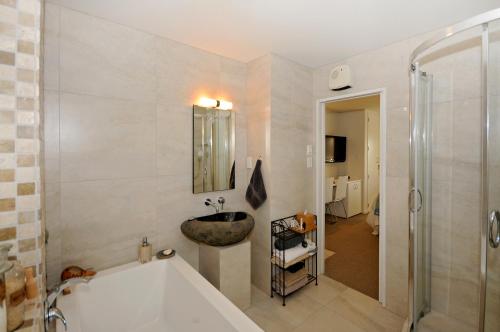 a bathroom with a tub and a sink and a shower at Kapiti Waves in Pukerua Bay