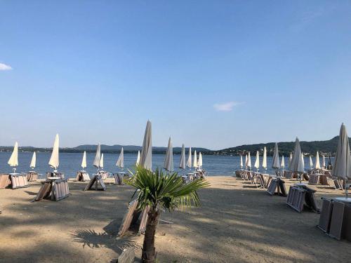 a beach with many chairs and white umbrellas at Villa Vista Lago in Massino Visconti