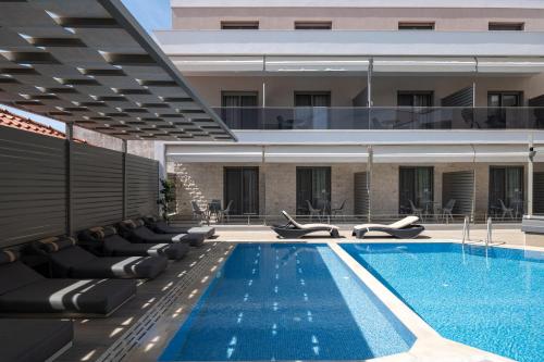 a swimming pool with lounge chairs next to a building at Leon Villas in Nikiti