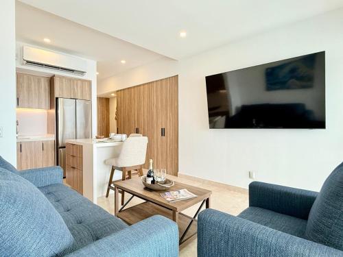 a living room with two blue couches and a kitchen at Beachfront family friendly 1 bdr NT505 in Puerto Vallarta
