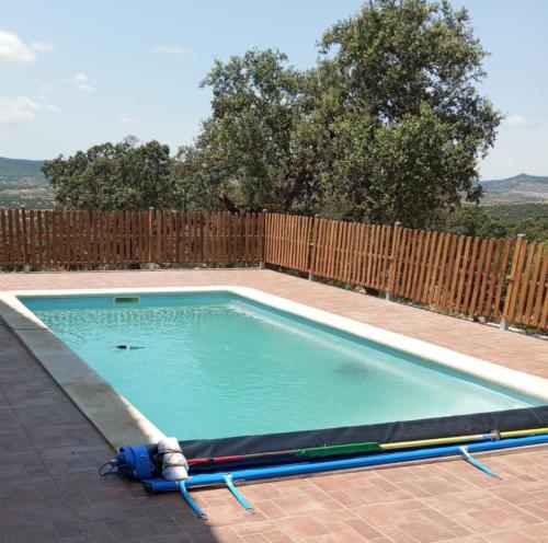 a swimming pool in a backyard with a wooden fence at Casa Rural Cortijo Torres in La Parra