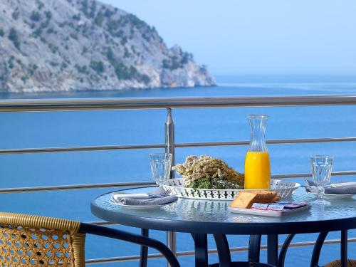 a table with a plate of food and a bottle of orange juice at Xenia Residence & Suites in Pili