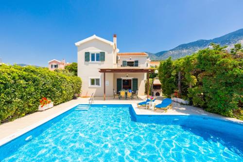 a villa with a swimming pool in front of a house at Villa Thalia Sofia in Mousata