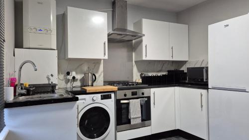 a kitchen with white cabinets and a washing machine at Modern Stylish Flat - Free Parking - Near London in Reading