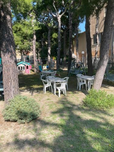a group of tables and chairs in a park with trees at Hotel La Terrazza in Porto San Giorgio