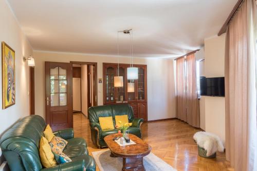 a living room with green leather furniture and a table at Apartmani Central 12 & Free parking in Vrnjačka Banja