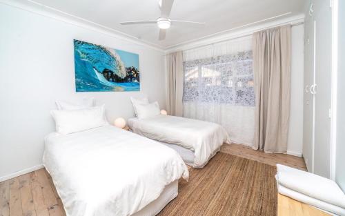 two beds in a white room with a window at Coastal Family & Pet friendly home in Ettalong Beach in Ettalong Beach
