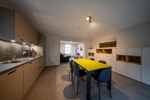 a kitchen with a yellow table and some chairs at Naturpark Gîte Al Schoulwunneng Sir in Boulaide