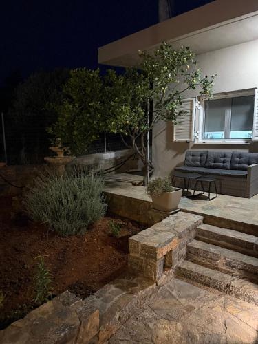 a house with a bench and stairs in the yard at Casa Negiada in Agios Nikolaos