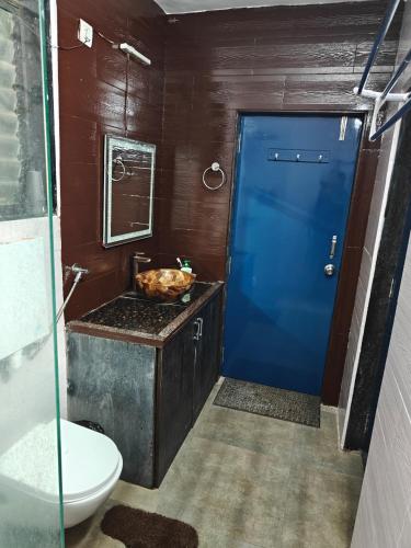 a bathroom with a toilet and a blue door at Sunils villa with private pool, Machan and play area in Karjat in Karjat