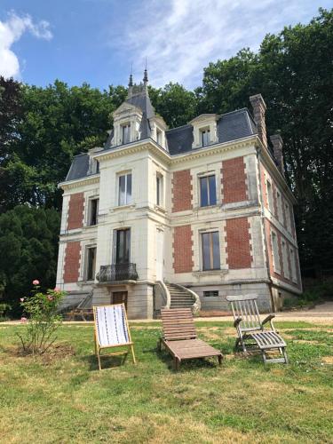 une vieille maison avec trois chaises devant dans l'établissement Château de la Françoisière, à Luceau