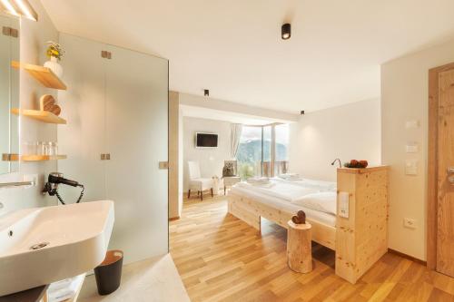 1 dormitorio con cama, lavabo y espejo en Herol - my mountain retreat, en Luson