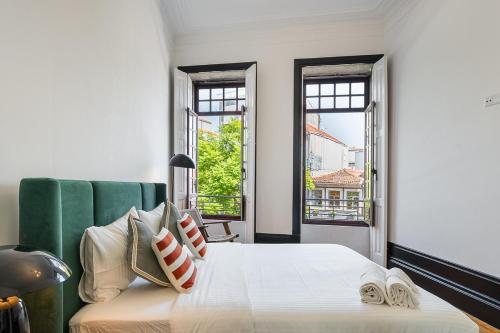 a bedroom with a white bed and two windows at Terraced Apartment in the Heart of Porto - Free Parking in Porto