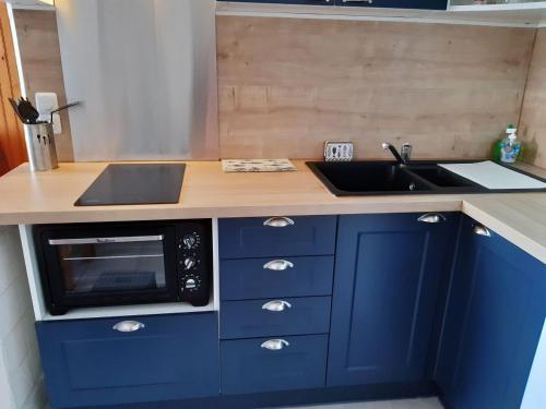- une cuisine bleue avec évier et four micro-ondes dans l'établissement Paisible appartement à deux pas de la Plage, à Saint-Hilaire-de-Riez