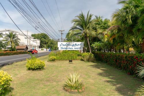 a sign on the side of a road with palm trees at Baan Faa Talaychan Resort in Chao Lao Beach