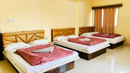 two beds in a hotel room with red sheets at Hotel Palash in Godarpura