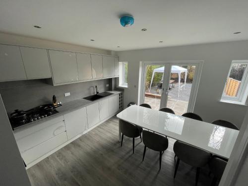 a kitchen with a white table and black chairs at Brand New High Spec House with Parking & Wi-Fi By Home Away From Home - B in Newcastle under Lyme
