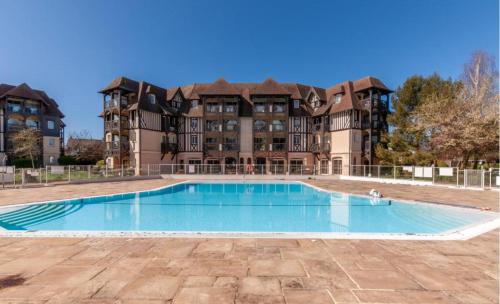 une piscine vide en face d'un grand bâtiment dans l'établissement L'Eagle Deauville - Residence du Golf, à Deauville