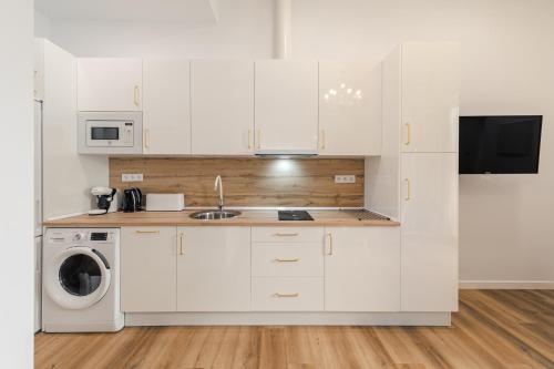 a kitchen with white cabinets and a washer and dryer at Luxury Apartment Mª Luisa Park & Plaza de España in Seville