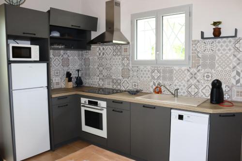 une cuisine avec un réfrigérateur blanc et un évier dans l'établissement Maison garde de barriere, à Canilhac