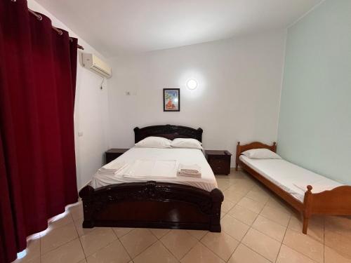 a bedroom with two beds and a red curtain at Donald Hotel in Vlorë