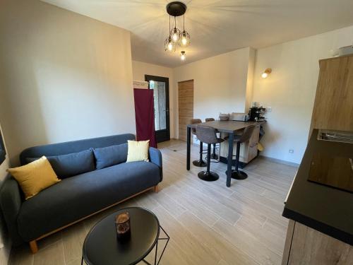 un salon avec un canapé bleu et une table dans l'établissement Charmant T2, centre village, à Vallon-Pont-dʼArc
