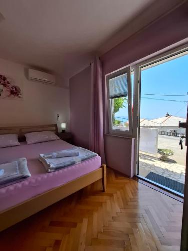 a bedroom with a bed and a large window at Guest House Pamela in Senj