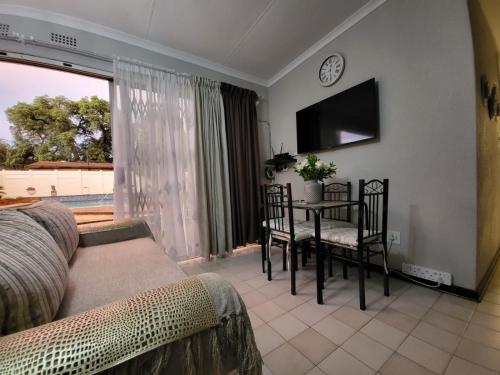a living room with a table and chairs and a clock at Villa Francisco Bed & Breakfast Solar Power in Germiston