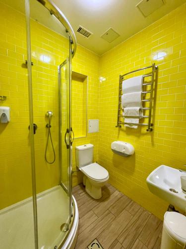 a yellow bathroom with a toilet and a shower at DREAM Hostel Lviv in Lviv
