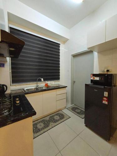 a kitchen with a sink and a black refrigerator at Homestay D'Casa, Apartment In Sepang, KLIA in Sepang