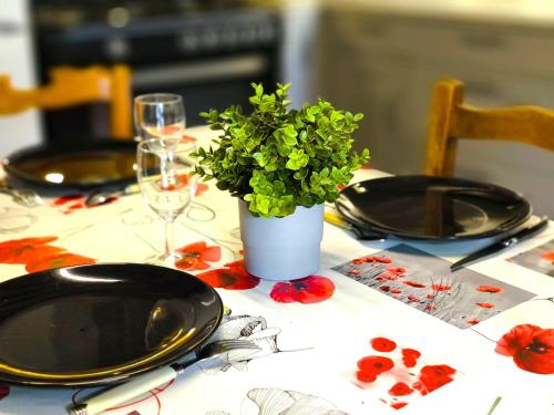 a table with plates and a vase with a plant on it at Authenticity Preserved in Brionne