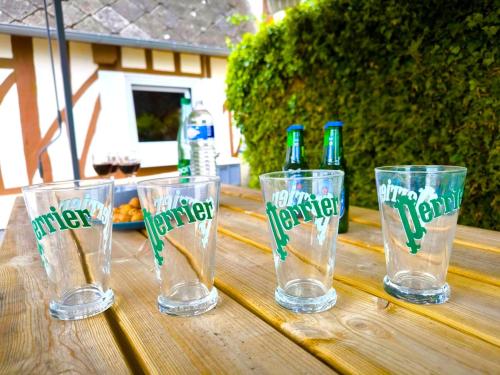 four empty glasses sitting on a wooden table with beer bottles at Authenticity Preserved in Brionne