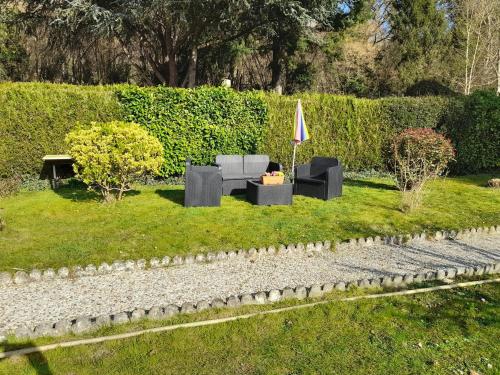 a garden with two couches and an umbrella at Authenticity Preserved in Brionne