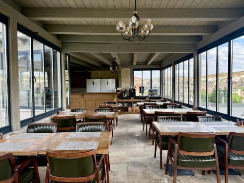 a restaurant with wooden tables and chairs and windows at Soho Cappadocia in Goreme