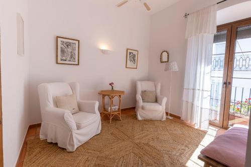 a living room with two white chairs and a table at La Morada Mas Hermosa in Marbella