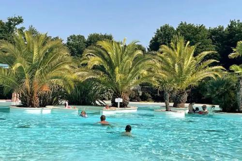 a group of people swimming in a pool with palm trees at Bassin d'Arcachon - Chalet VIP 5 personnes in La Teste-de-Buch